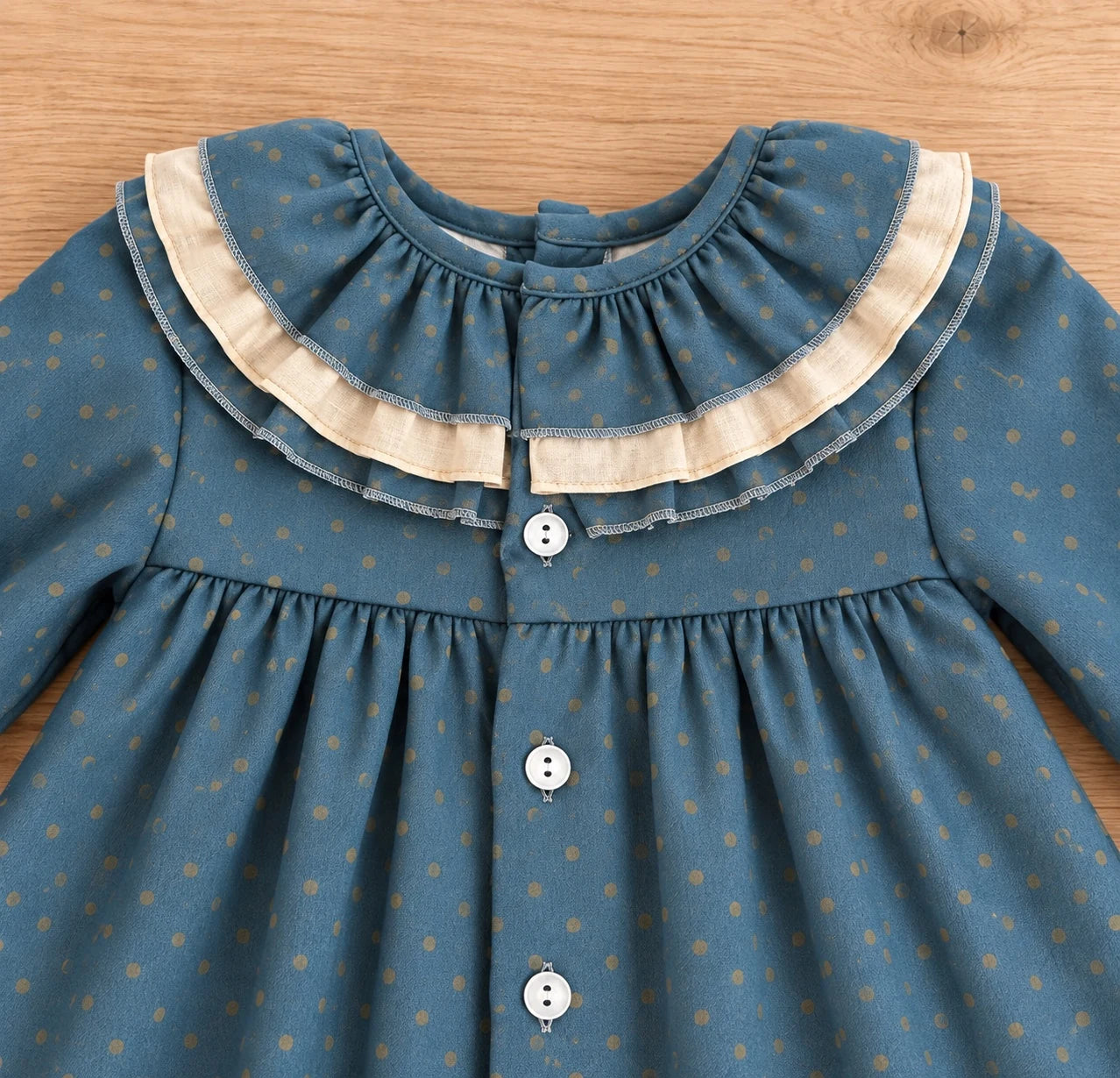 Detalle de cuello con doble volante beige de vestido de niña azul petróleo